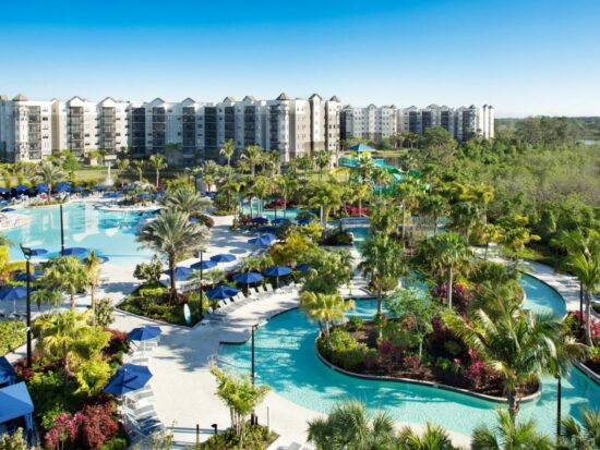 outdoor view of a pool snaking outside of a water park resort in orlando with palm trees and blue sky