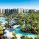 outdoor view of a pool snaking outside of a water park resort in orlando with palm trees and blue sky