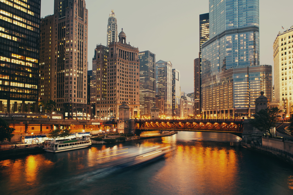 A moody view of Chicago on a cloudy day as the sun starts to set with the building lights on