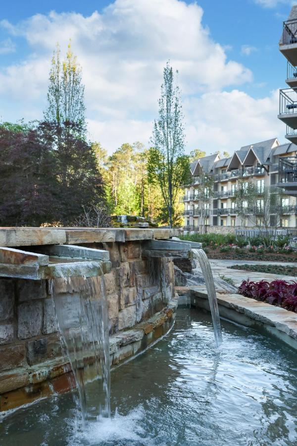 a beautiful rock fountain with a building in the background, decorated with beautiful trees and landscaping at one of the resorts in Georgia