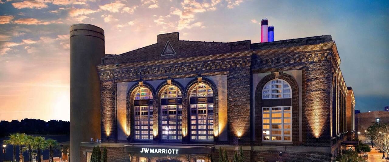 outside of the JW Marriott resort in Savannah a purple lit building with smoke stacks on a sunset evening