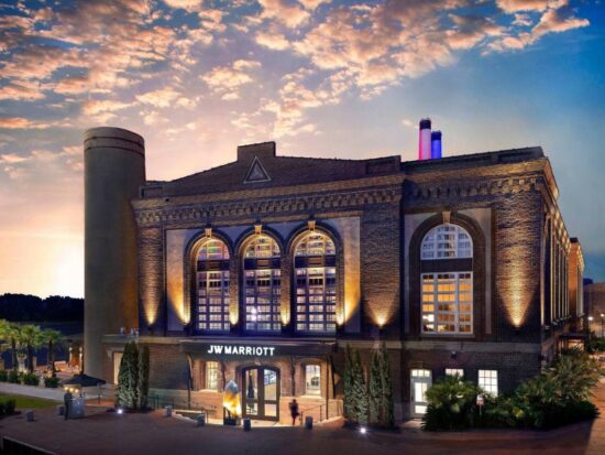 outside of the JW Marriott resort in Savannah a purple lit building with smoke stacks on a sunset evening