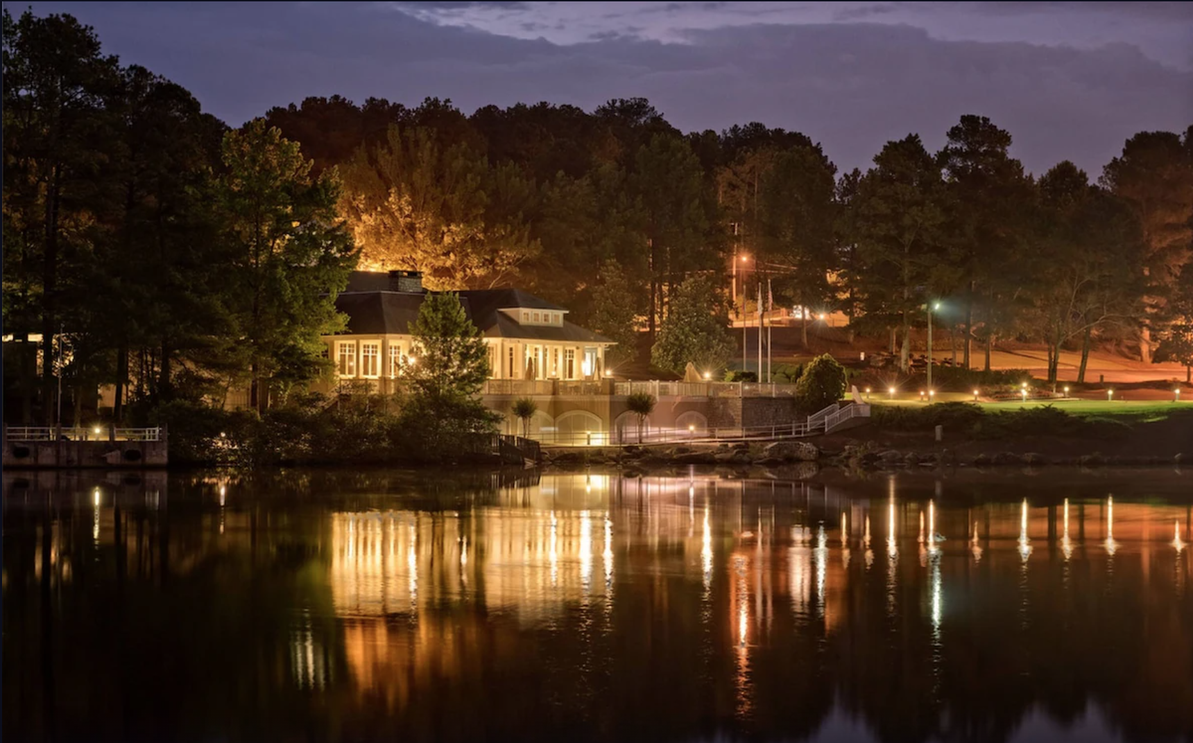 an evening image off the water of a beautiful building illuminated by bright lights and path to the water, one of the resorts in Georgia!