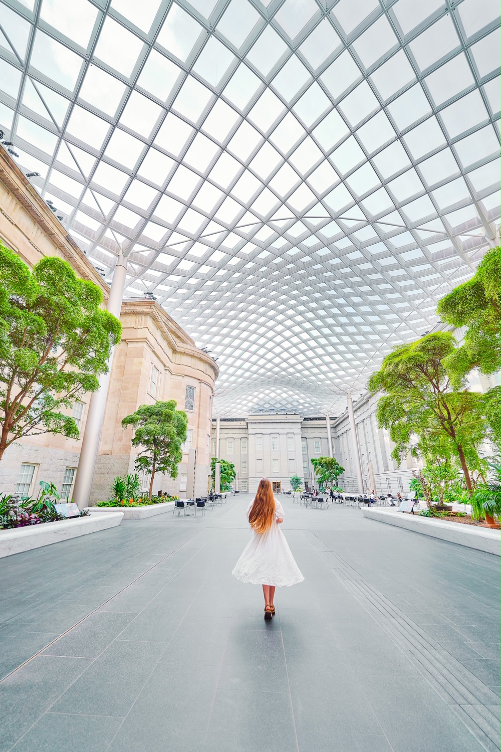 A woman in a white dress standing in a huge lobby of a museum best things to do in the usa