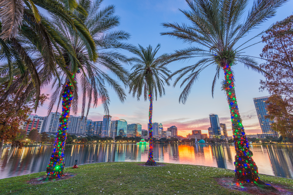 Palm tress decorated with Christmas lights surround Lake Eola at sunset, a beautiful place to see Florida Christmas lights!