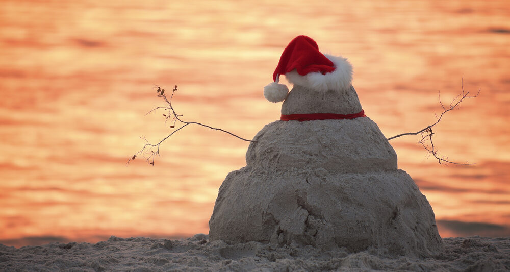 Snowman made of sand with a Santa hat on the beach in Florida.