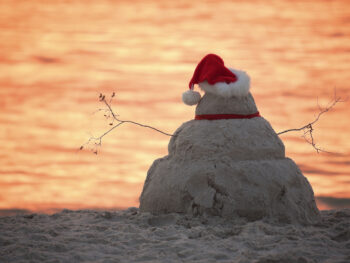 Snowman made of sand with a Santa hat on the beach in Florida.