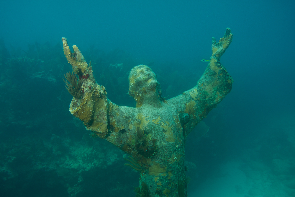 An underwater sculpture of Jesus with his hands raised