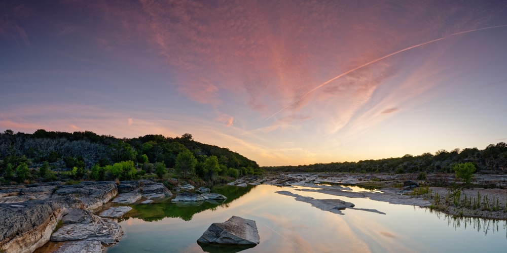 a colorful sunset in the texas hill county area with a lake. this is one of best weekend getaways in Texas! 