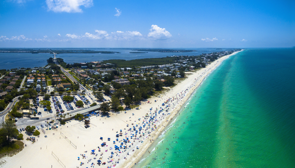 the Anna Maria island beach with beautiful blue water and a sandy white shore. your an see the island in whole here. 