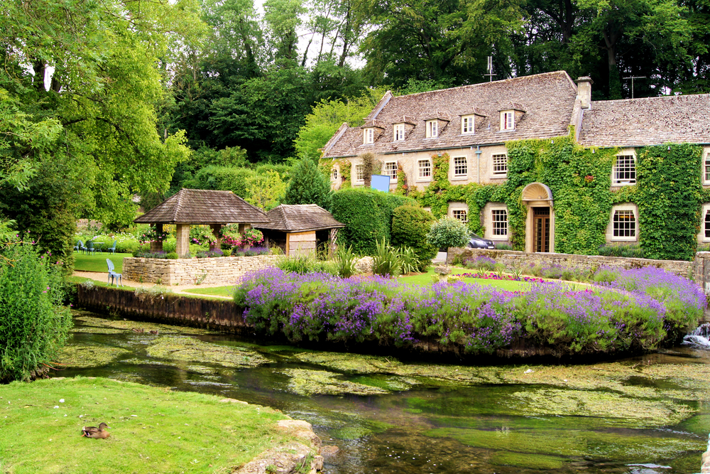 Picturesque garden in the Cotswold village of Bibury, England with the river in front. 