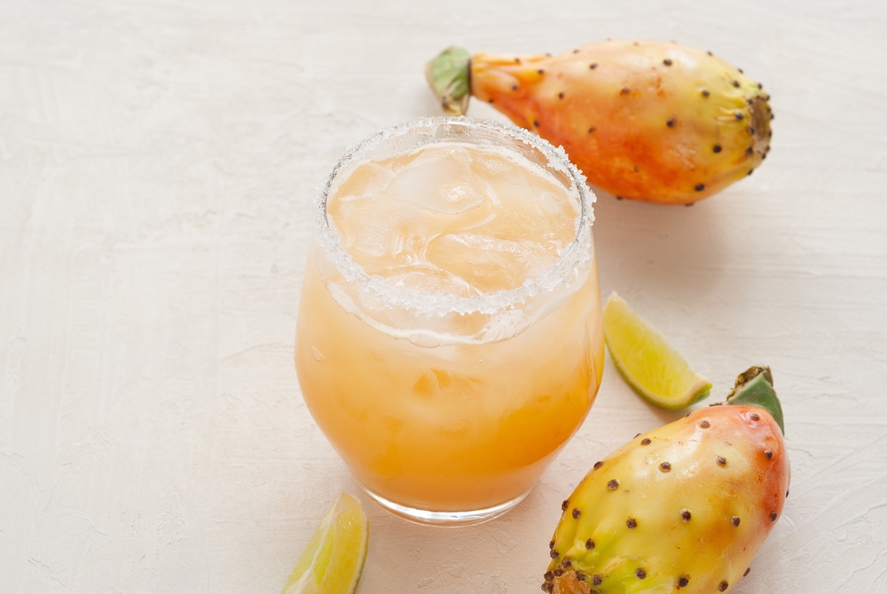 beautiful rich orange yellow cocktail with a salt rimmed glass and prickly pears on either side! a lovely signature drink to try while trying all the best restaurants in san antonio!