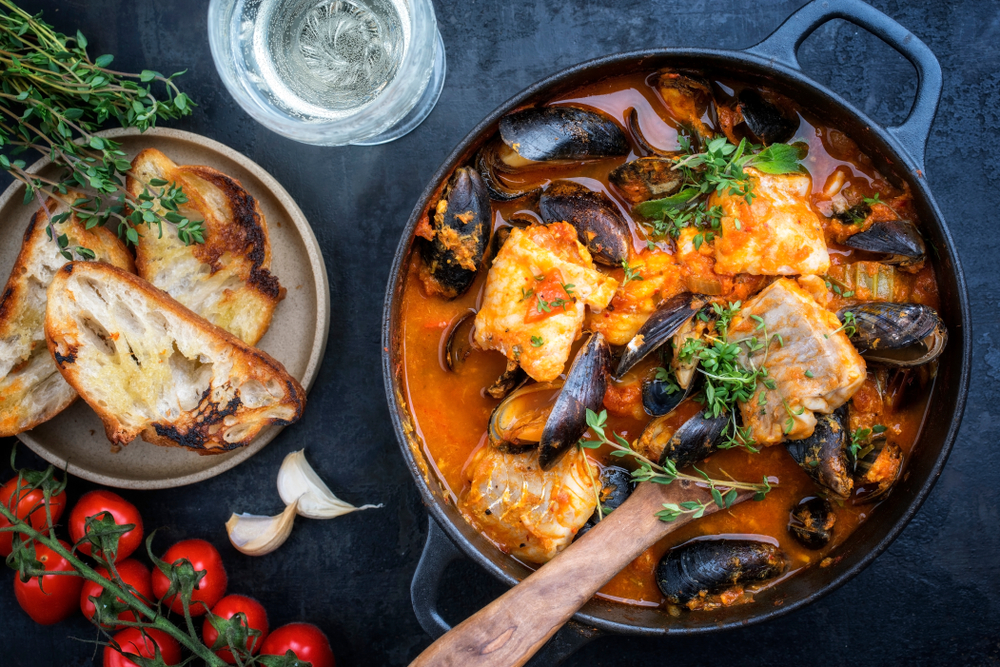 a rich dish filled with fish and mussels and a tomato stewed sauce with toasted sourdough bread, a perfect example of french cuisine featured at this lovely option for the best restaurants in san antonio