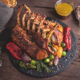 steal and vegetables on a black plate with brown background at a san antonio restaurant