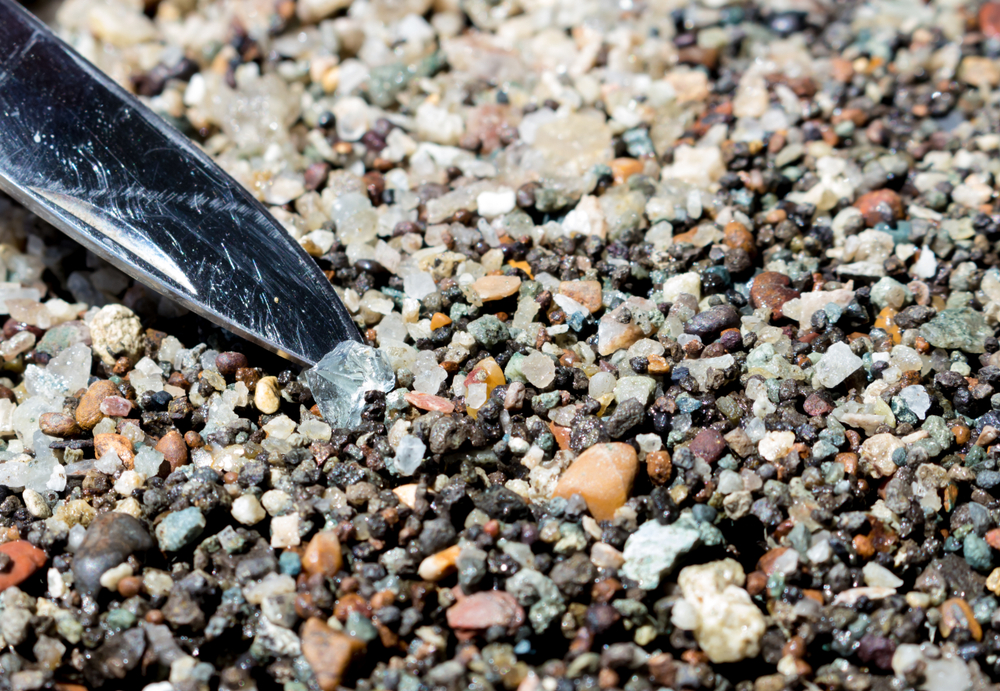 A trowel lifting a clear stone out of many tiny pebbles at Crater of Diamond State Park, one of the best things to do in Arkansas! 