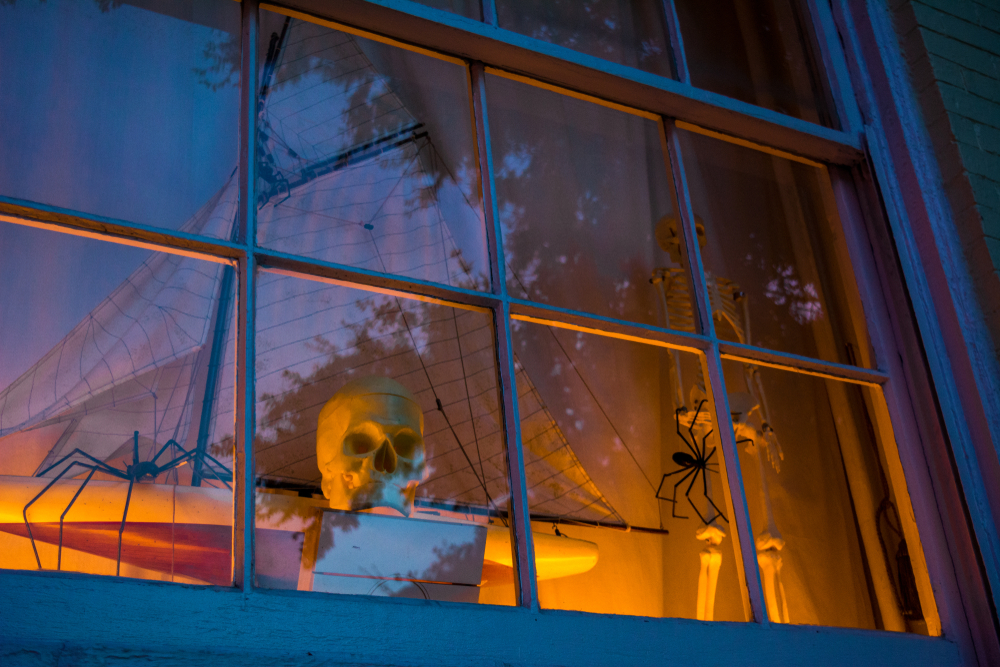 backlit with warm lighting, this spooky window is decorated with large spindly spiders and skeletons making for a very spooky display!