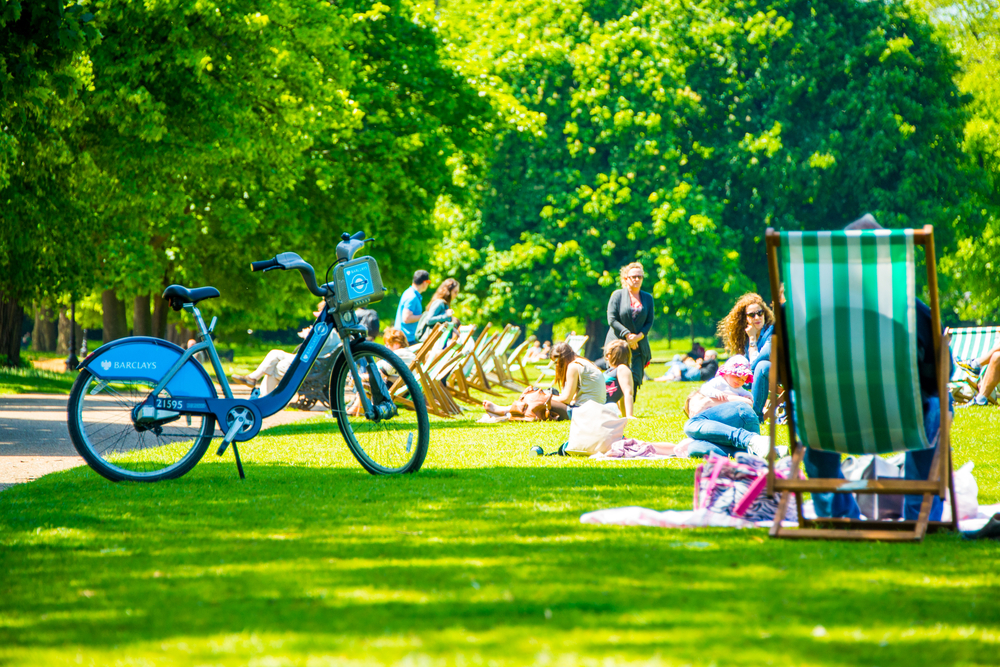 Hyde park in London during warm sunny day. People sitting on the grass having lunches. The best time to vissit London. 