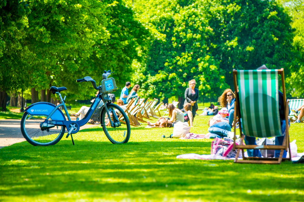 Hyde park in London during warm sunny day. People sitting on the grass having lunches. The best time to vissit London.