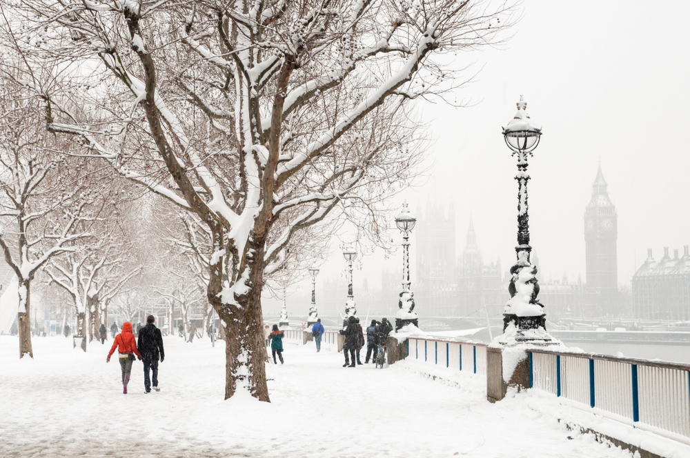 London snow scene during cold winter weather. The ground is covered in snow and you see across the river to Big Ben.