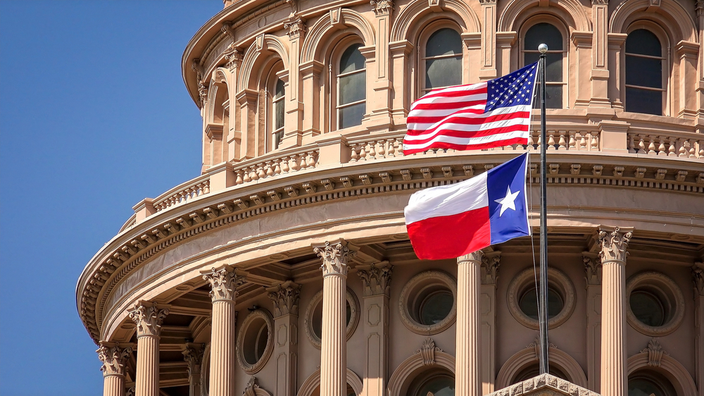 a photo with the American and texas flags flying in front of an old building in Texas 