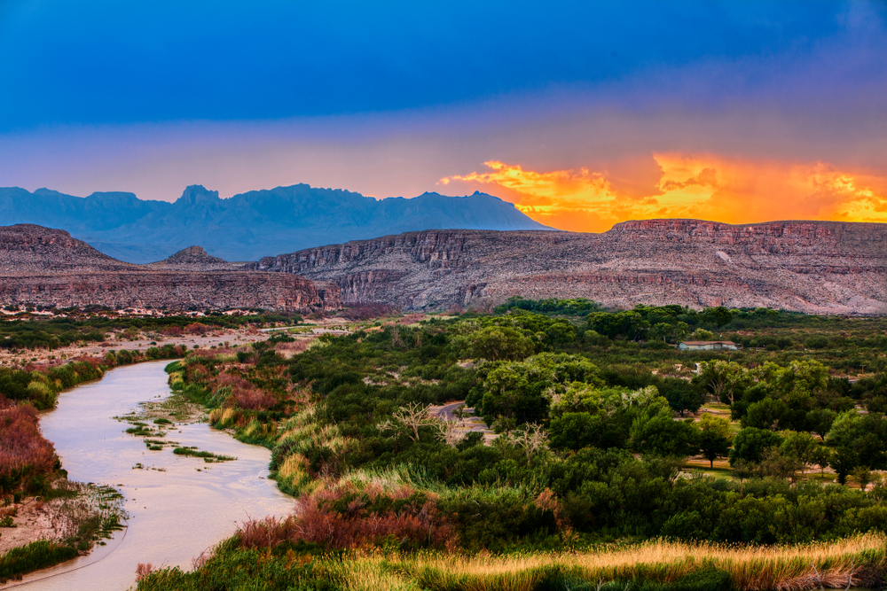 a beautiful field at Big Ben national park at sunrise with the golden sun popping up from behind the colorful mountains.