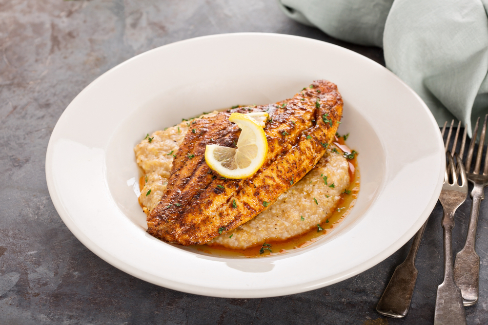 A plate of fish and grits with cajun seasoning