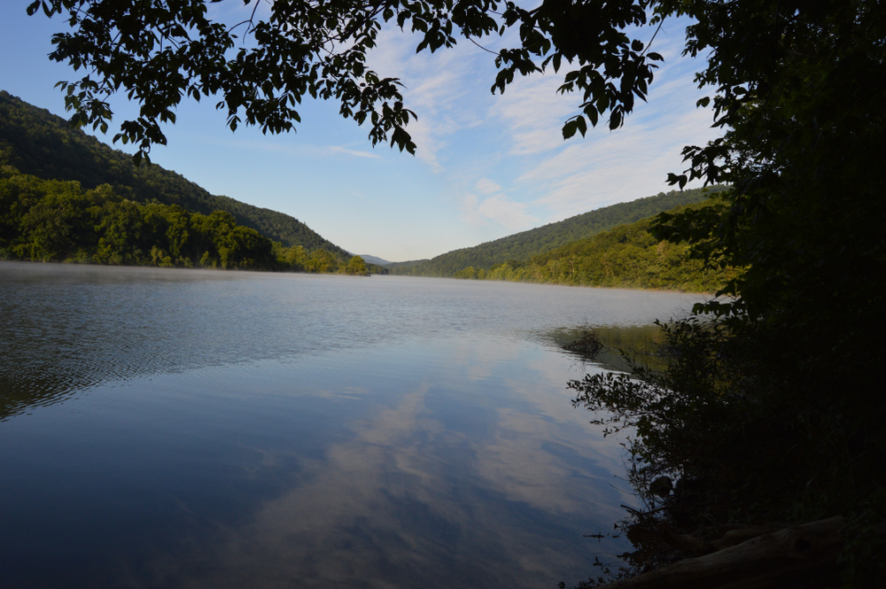 a photo of the gorgeous lake moo maw in Virginia. the mountain tops are green and the lake is very calm. 