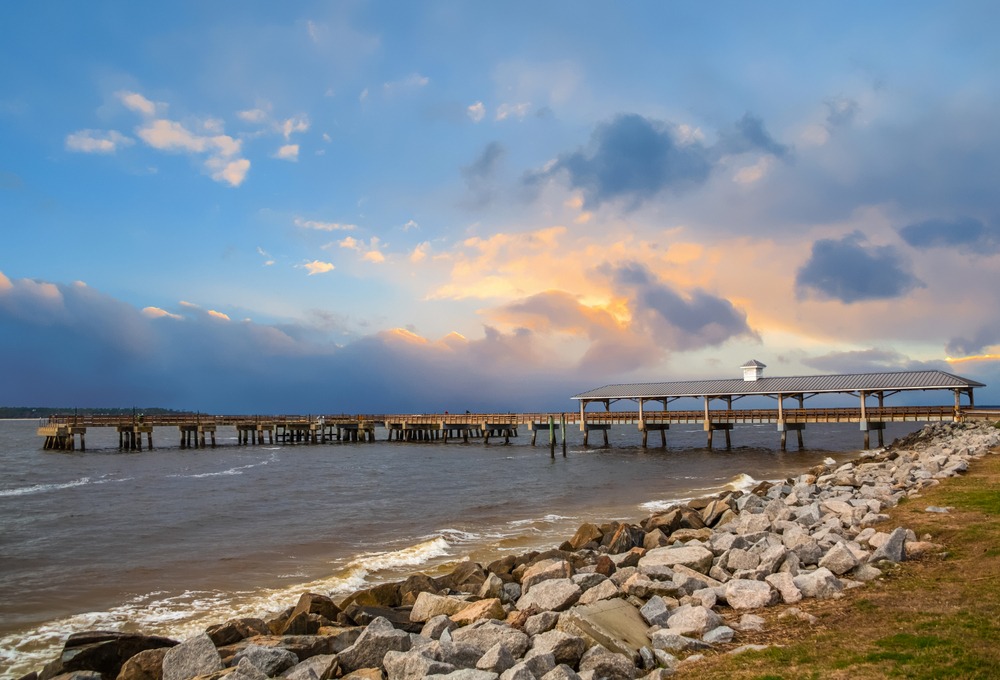 the old St. Simons fishing pier along a rock bed against the water with overcast skies 