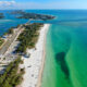 view of green and blue water with white sand beach from above on anna maria island