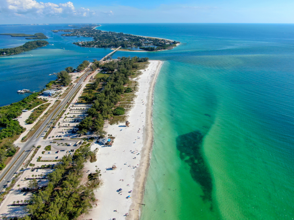 An overhead shot shows the long strips of white sand and green water at Coquina Beach. 