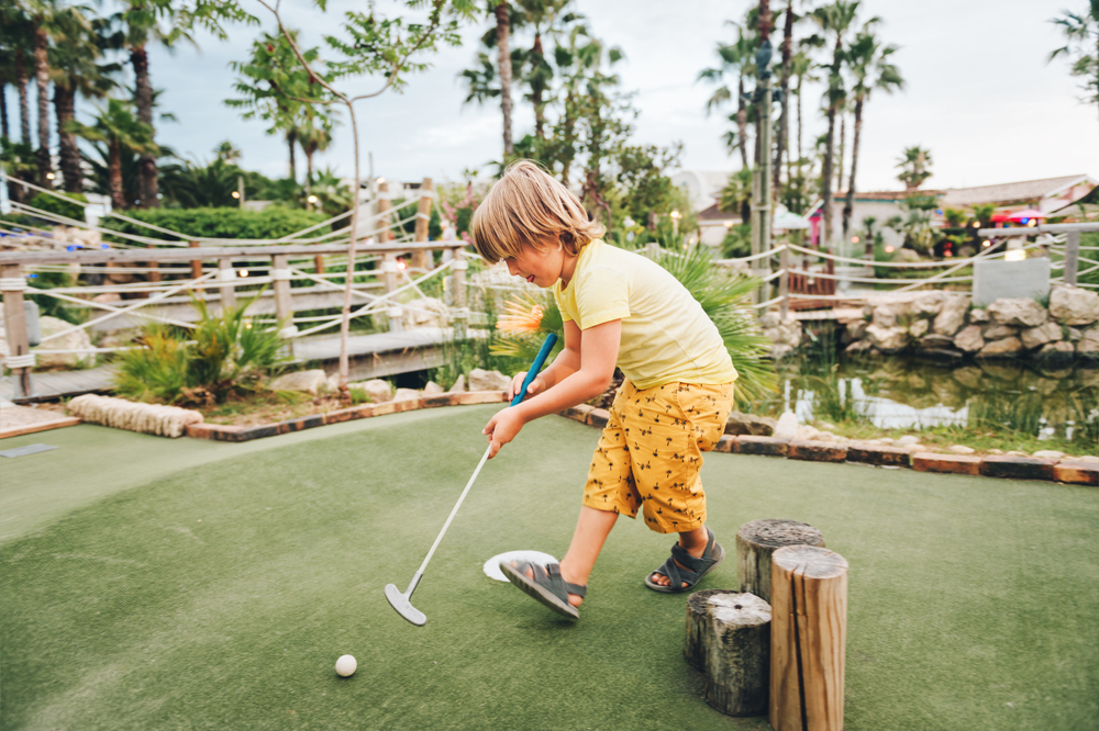 A young child enjoys Putt Putt, chasing after a ball, which is one of the things to do in Anna Maria Island after a beach adventure! 