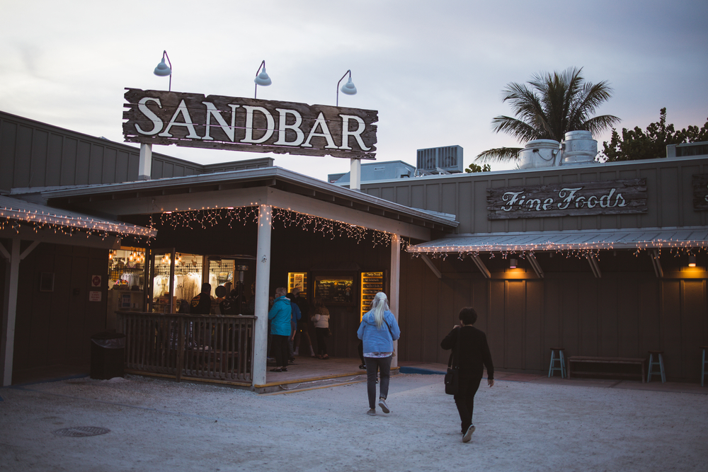 Families enter the sandbar, which is one of the things to do in Anna Maria Island. This restaurant allows you to eat on the beach and enjoy the sunset!