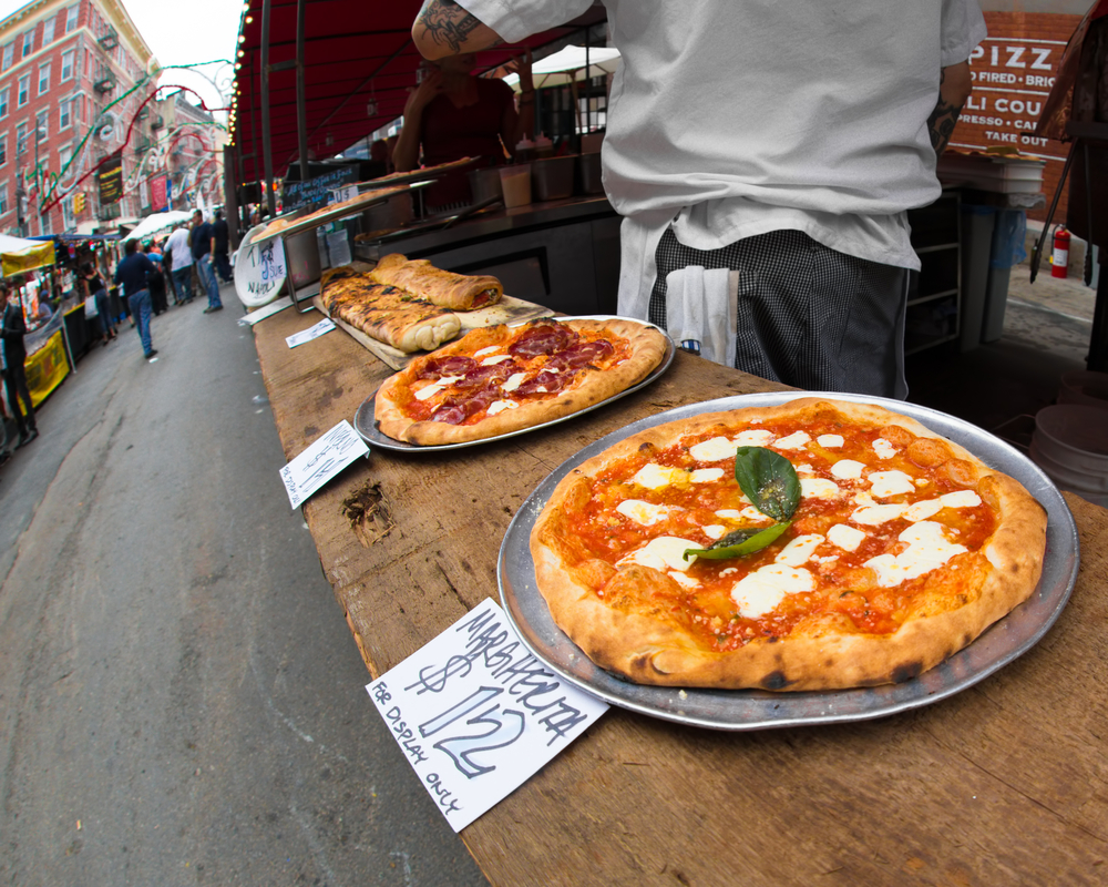 three pizzas all lined up in a row on a street corner in NYC you have to try pizza during your weekend in NYC 