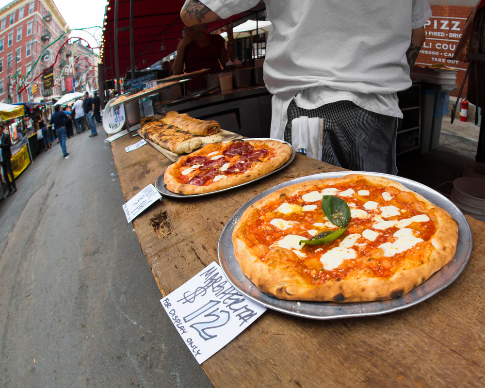 three pizzas all lined up in a row on a street corner in NYC you have to try pizza during your weekend in NYC