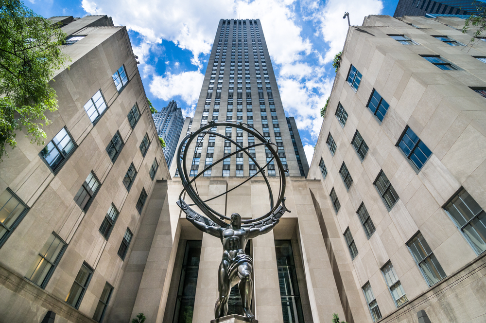 the front of the Rockefeller center in NYC. there is a metal ball out front in a beautiful design