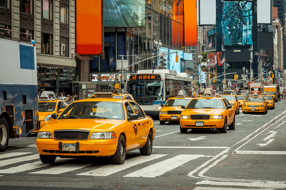 a bunch of yellow taxi cabs in NYC driving down the street. this is one of the best ways to get around during your weekend in NYC
