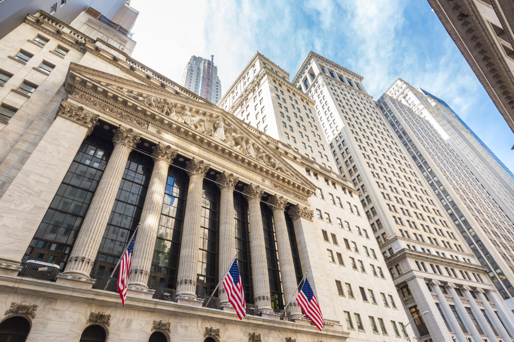 the beautiful building on Wall Street with American flags out front and beautiful old buildings