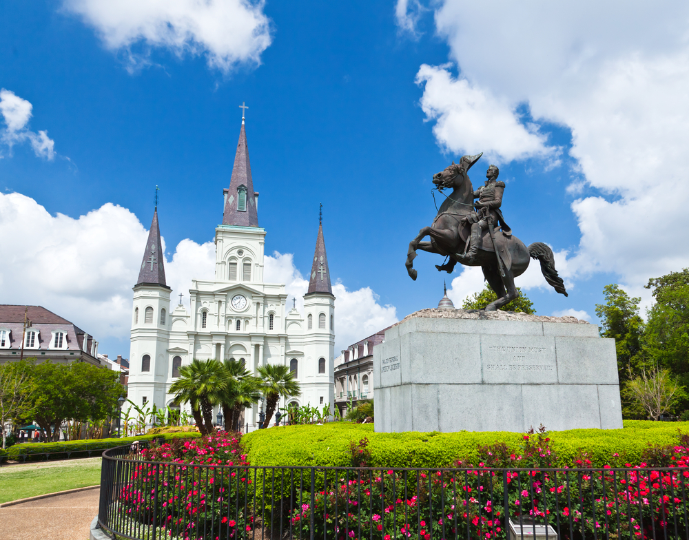 Jackson Square in New Orleans with Jackson statue on a horse surrounded by flowers with the background of t the church