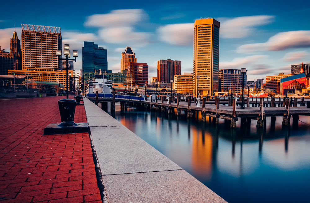 the beautiful view of the Baltimore Inner Harbor at sunset with the beautiful buildings reflecting into the water.
