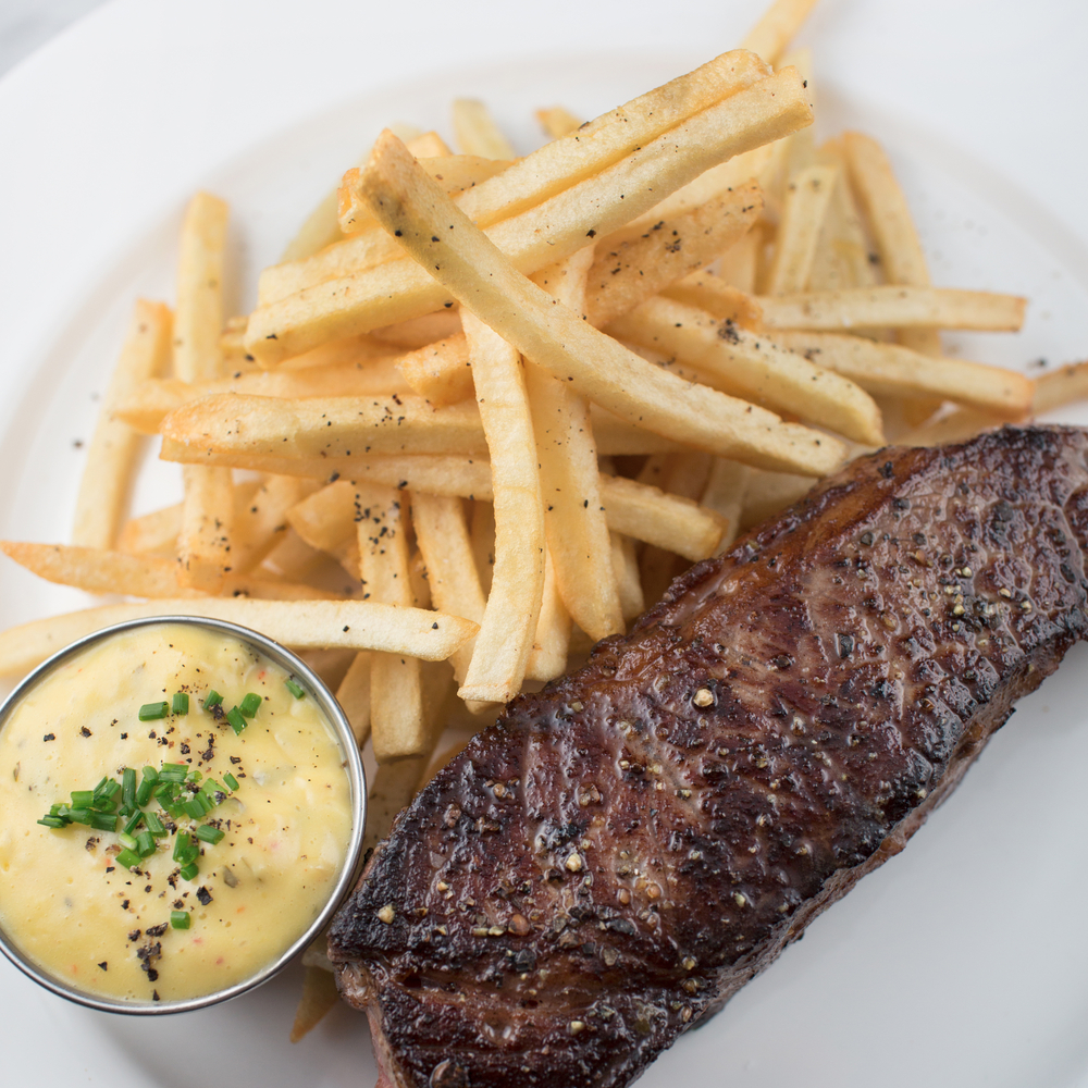 steak and fries on a plate served wit bernaise sauce