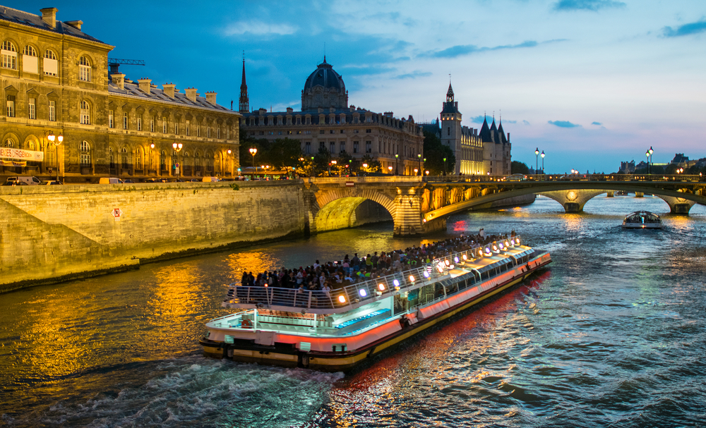 A river cruise boat floating down the Seine River at nighttime