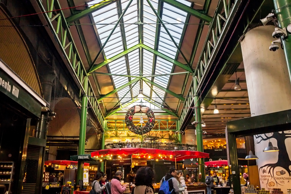 People shopping at the Borough Market with a big wreath hanging overhead.