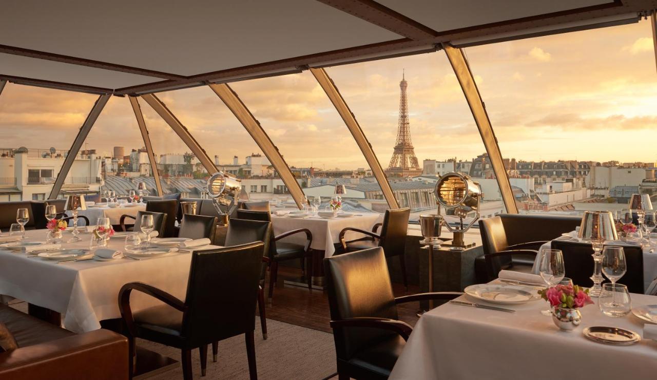 Golden sunset over Paris with the Eiffel Tower seen from a dining area with floor to ceiling windows at the Hotel The Peninsula Paris.