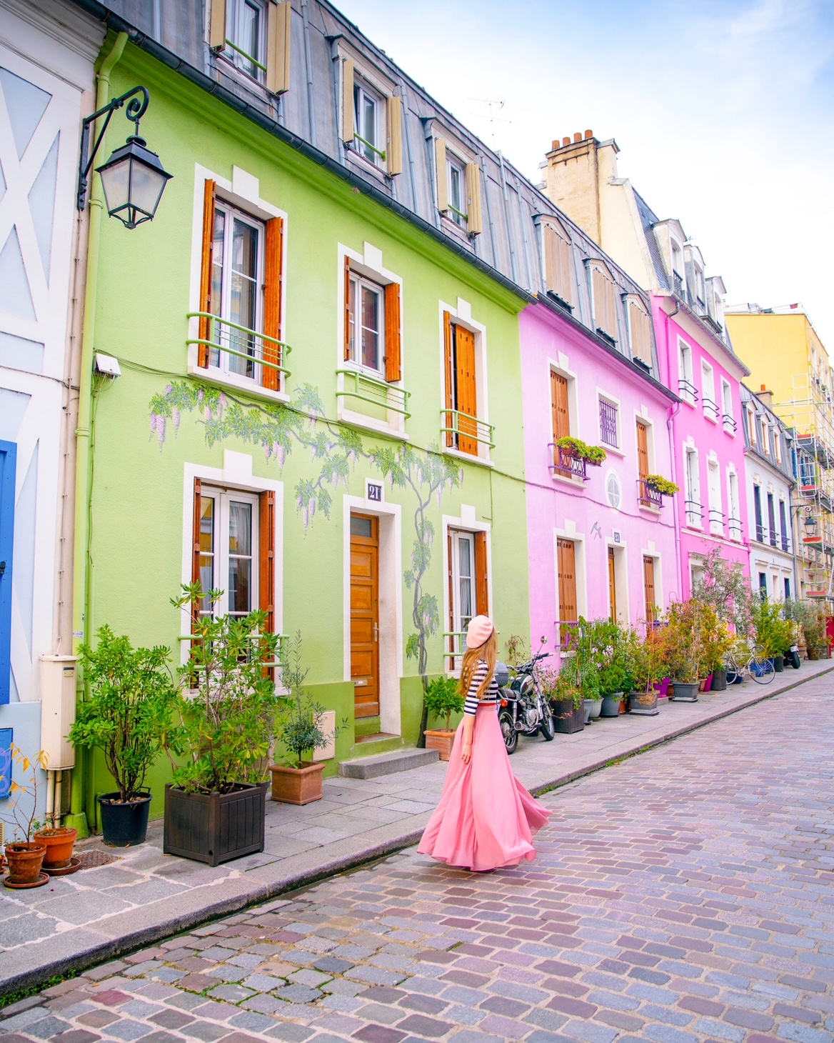 A girl in a pink beret and pink skirt standing in front of the colorful houses on Rue cremeux on what to do with 3 days in Paris