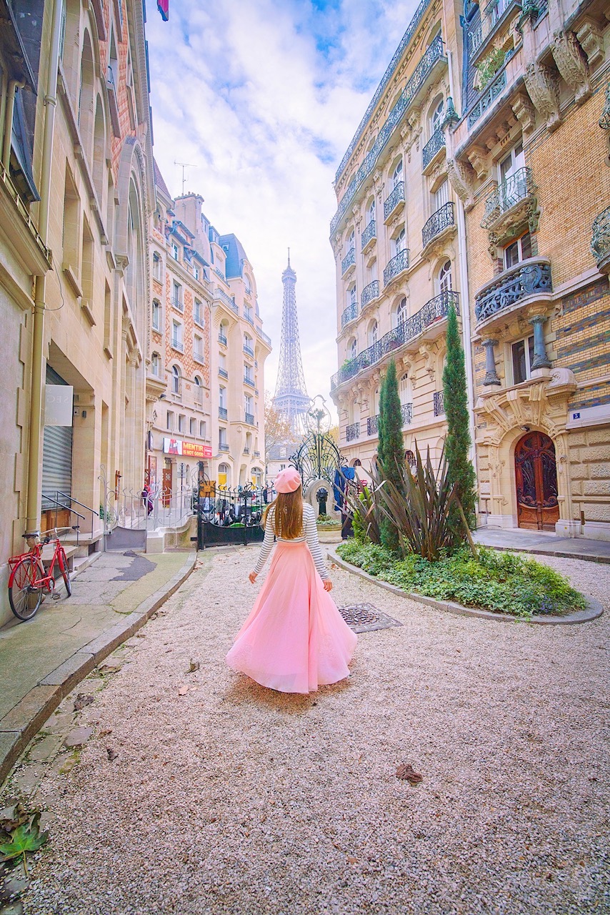 A girl in pink looking on the Eiffel Tower in the background surrounded by buildings