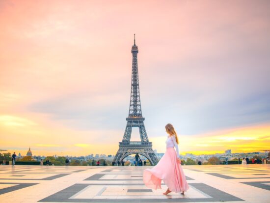 a girl in a pink skirt dancing in front of the Eiffel Tower at Sunrise
