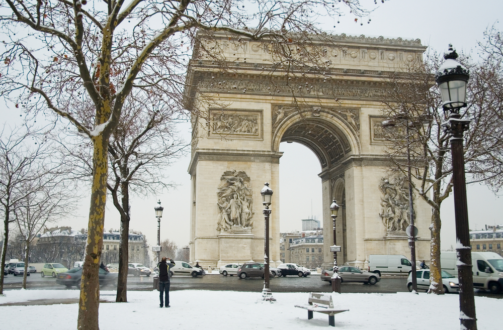 View of the Arc de Triomphe with bare trees and snow on the ground.