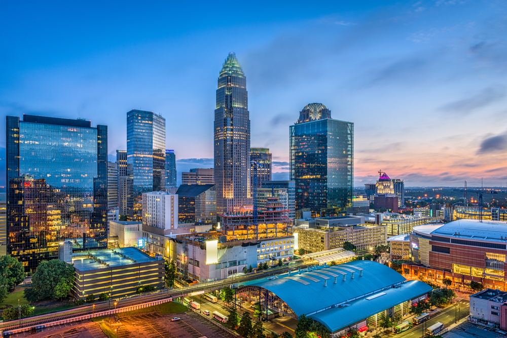 downtown Charlotte at night with the sun barely present on the right side of the sky, with the skyline lit up 