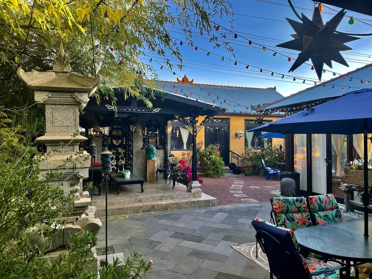 View of the eclectic and Bali inspired outdoor seating area with colorful lights and a pagoda inspired sculpture.