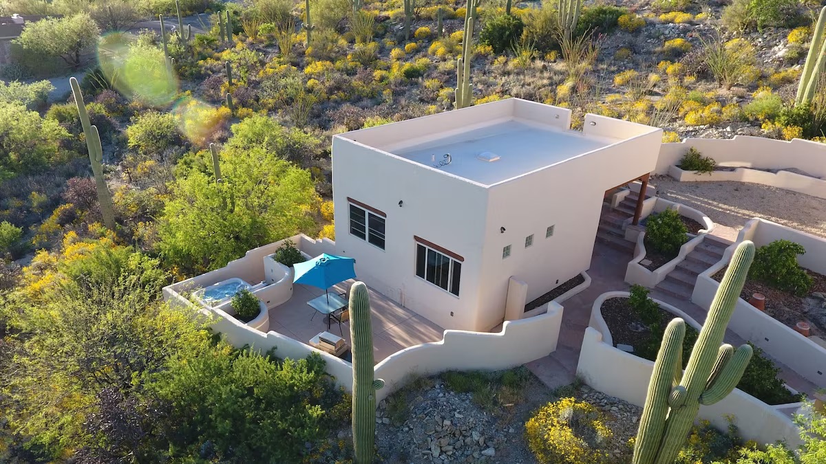 View of the towering cactuses and desert surrounding this airbnb in tucson. The hot tub and private back patio are visible in this aerial photo. 